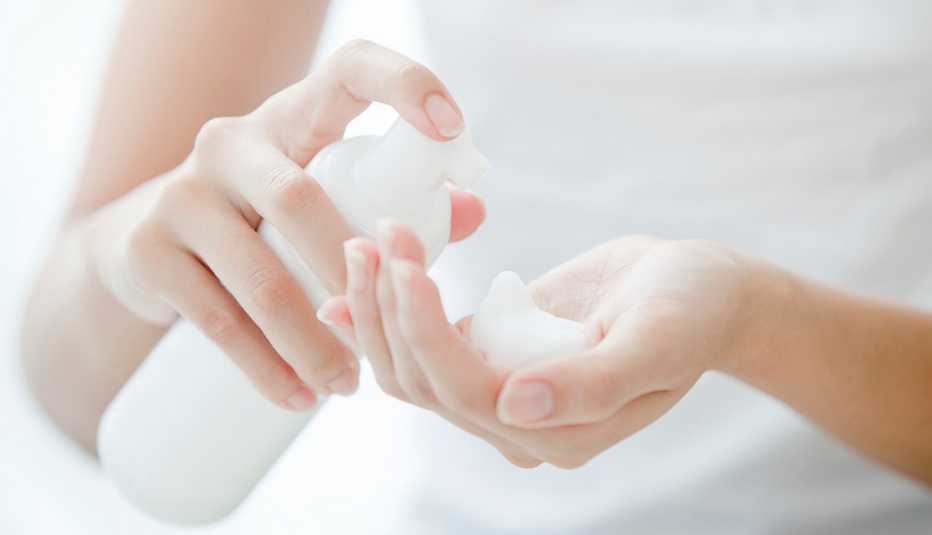 Mujer poniéndose crema limpiadora facial en su mano
