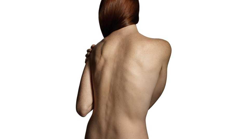Mujer de espaldas, desnuda y agarrándose un hombro - Formas de manejar el dolor