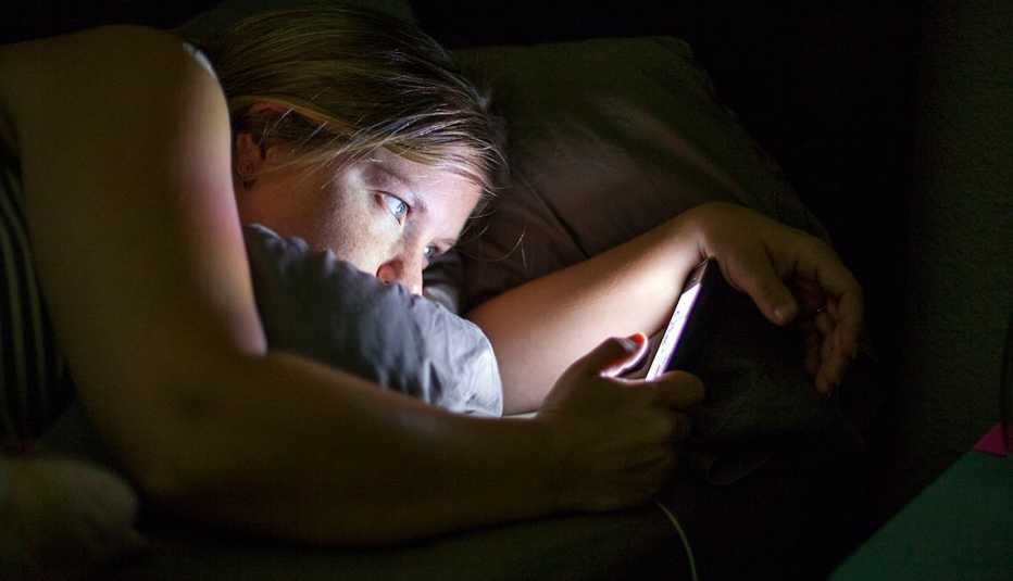 Mujer mirando su celular en la noche