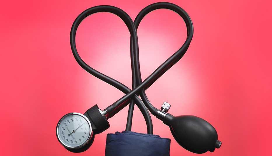 El cordón de un aparato para medir la presión forma un corazón sobre un fondo rojo