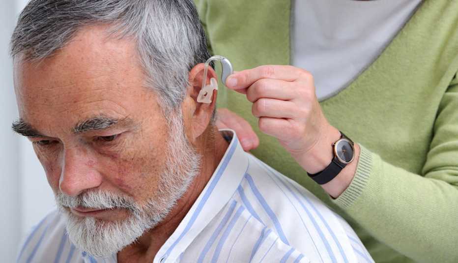 Médico colocando un audífono a un paciente - Pérdida de audición