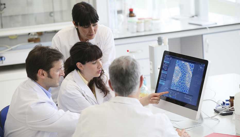 Cuatro científicos miran a una computadora