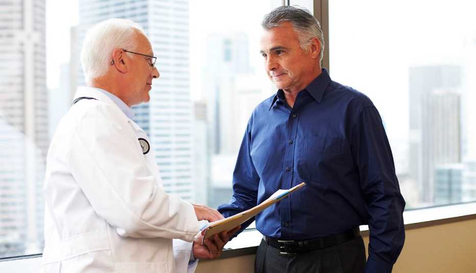 Doctor mira un informe médico con un paciente.