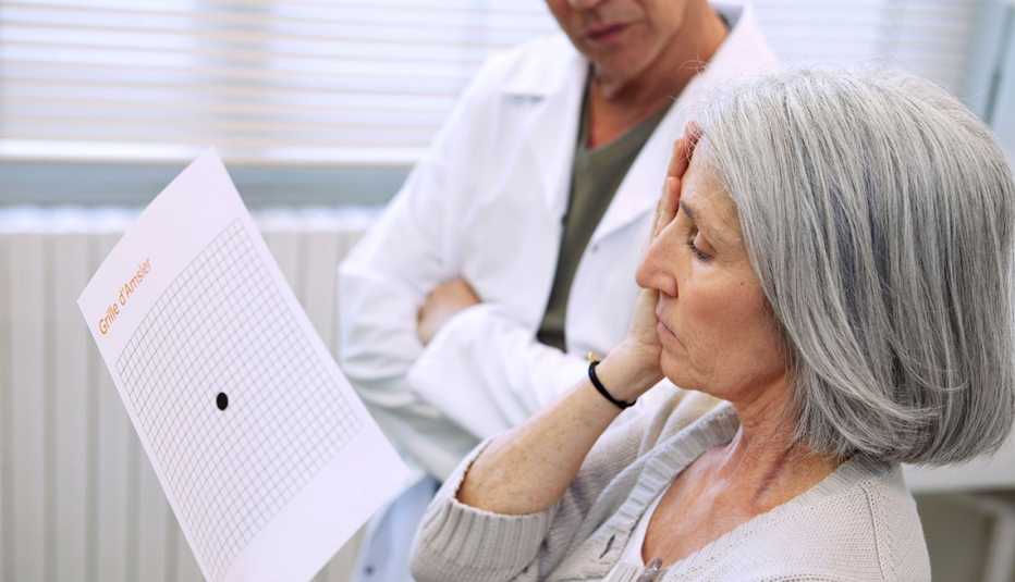 Mujer lee mientras se cubre un ojo en un examen de la vista
