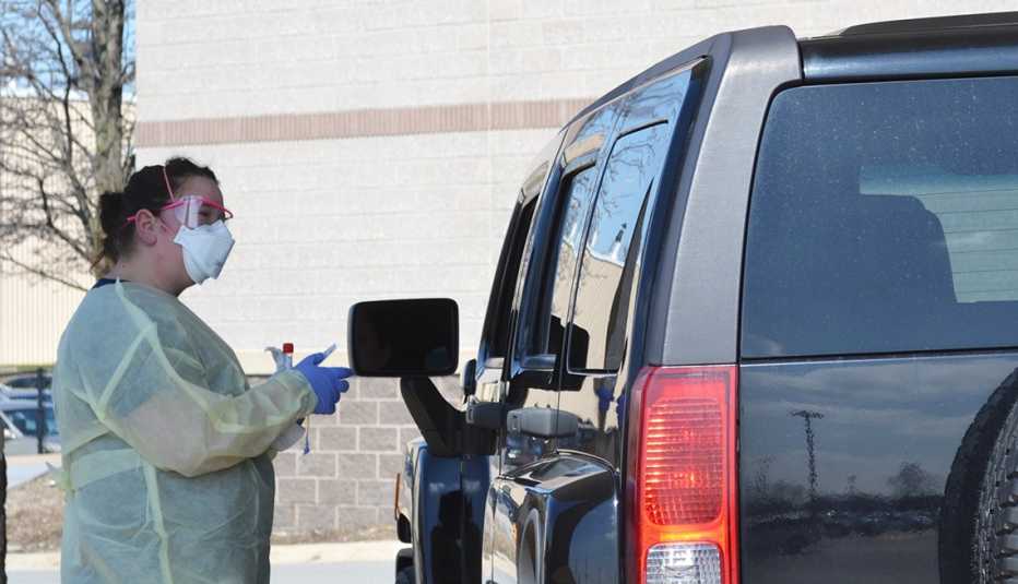 La enfermera Jennifer Homan asiste a una persona en su auto durante el brote de coronavirus
