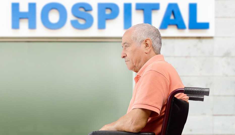 Hombre en sillón de ruedas frente a un hospital