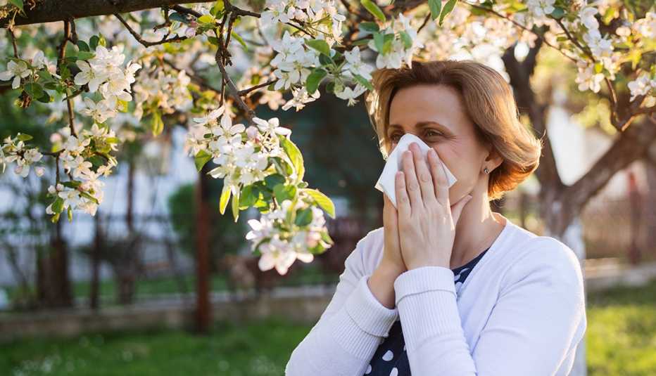 Una mujer cubre un estornudo con una servilleta