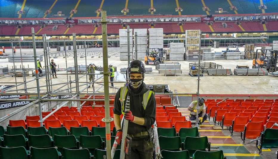 Un hombre con mascarilla construye un andamio para un hospital temporal en el estadio Principality en Cardiff, Gales
