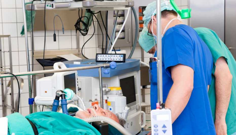 Dos médicos usando equipo protector mientras un paciente permanece conectado a un ventilador