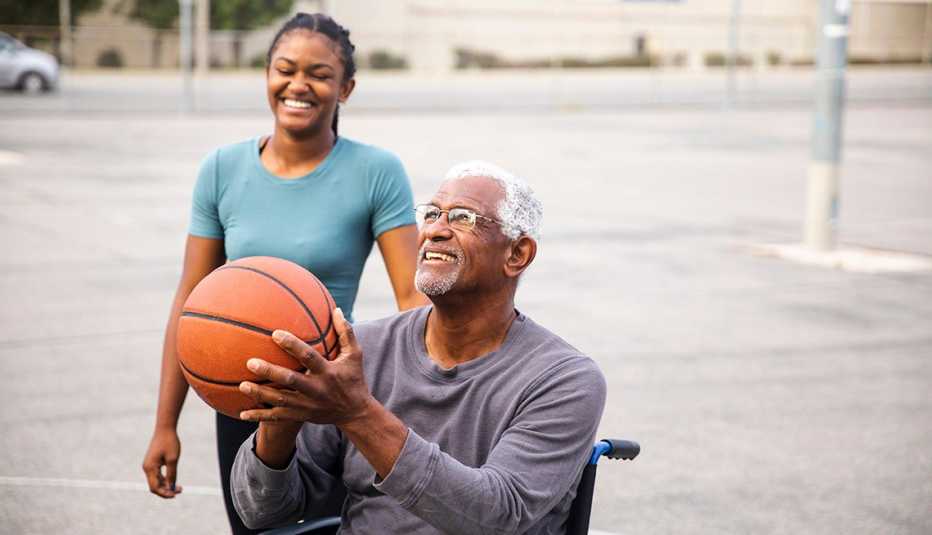Hombre en silla de ruedas tira una bola de baloncesto mientras una mujer lo observa