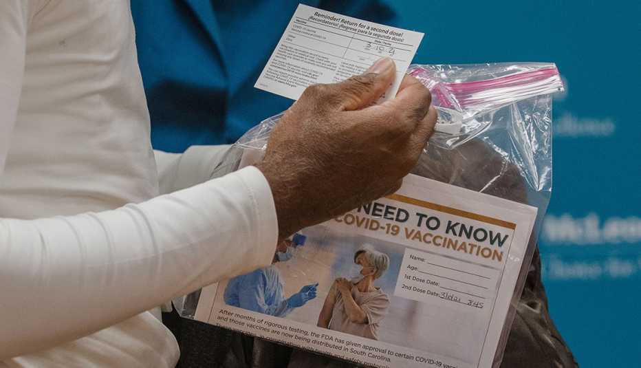 Un paciente sostiene una tarjeta de vacunación y un paquete de información después de recibir la vacuna contra la COVID-19