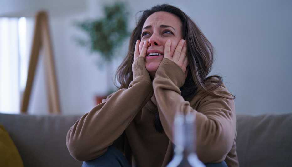 Una mujer llora sentada en un sofá