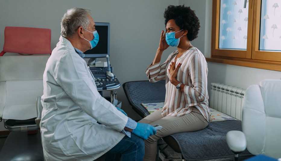 Un médico examina a una paciente que usa mascarilla