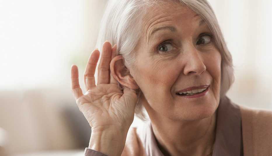 Una mujer lleva su mano al oido para escuchar mejor