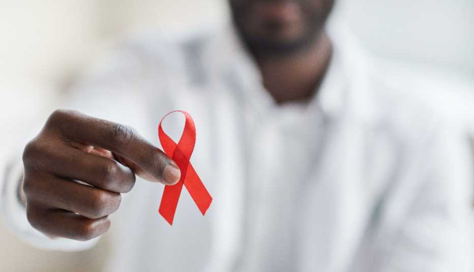 Un hombre sostiene un lazo rojo, símbolo del Día Mundial del SIDA