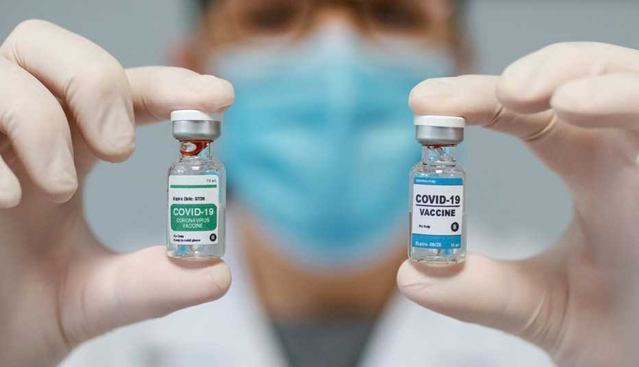 Un médico sostiene dos frascos de vacunas contra la COVID-19