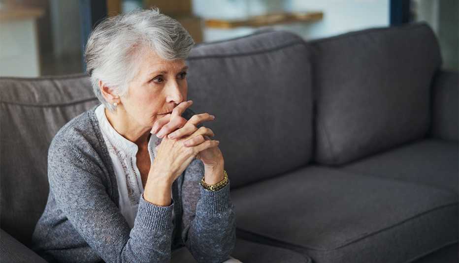 Una mujer mayor preocupada sentada en un sofá