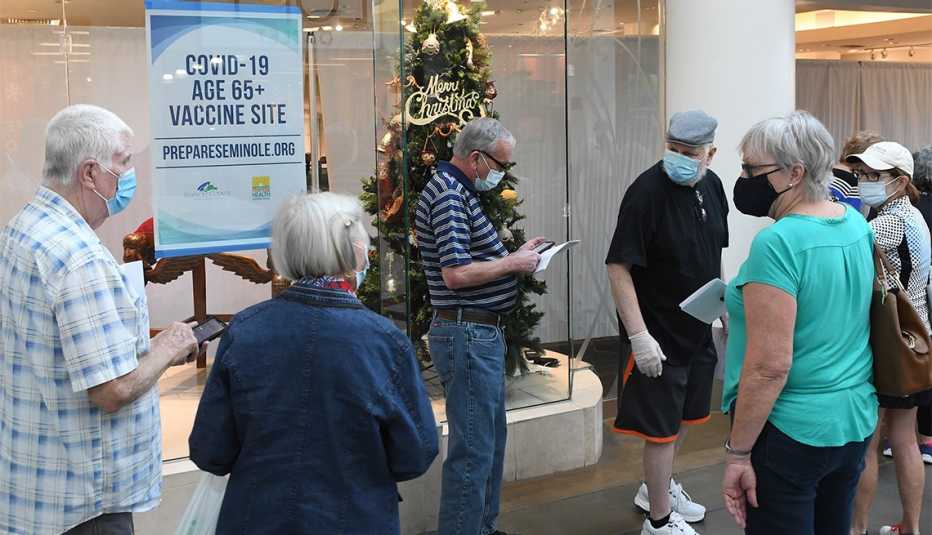 Un grupo de personas mayores esperan en una fila en la víspera de Año Nuevo para recibir una vacuna COVID-19 en una tienda desocupada en el Oviedo Mall en Oviedo, Florida.