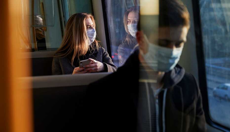 Pasajeros en un autobus usando mascarillas