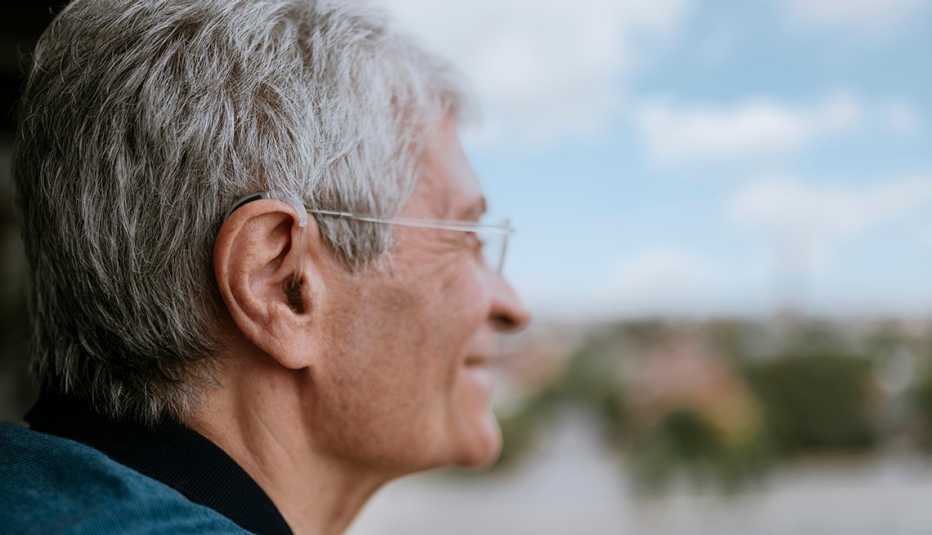 Un hombre, visto de perfil, usa audífonos para escuchar mejor