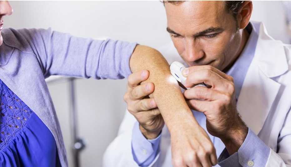 Un dermatólog examina la piel del brazo de una mujer