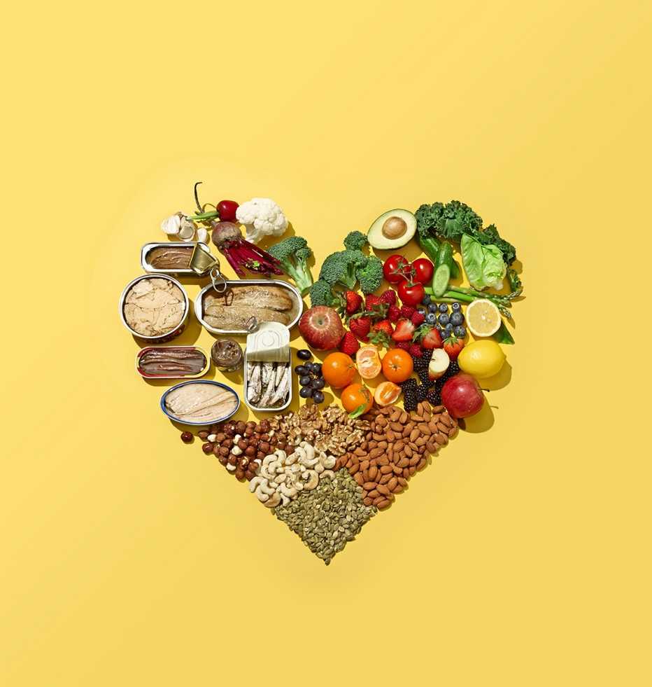 Alimentos saludables, de varios grupos, forman un corazón sobre un fondo amarillo