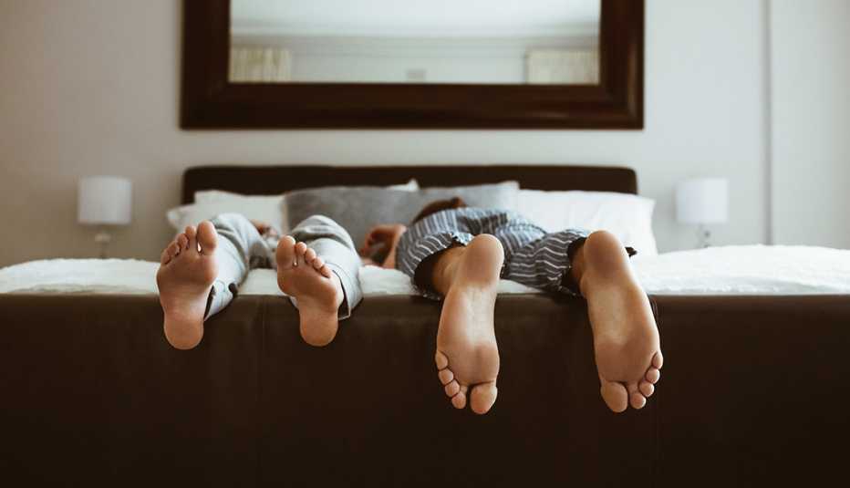 Dos pares de pies de dos personas acostadas en una cama