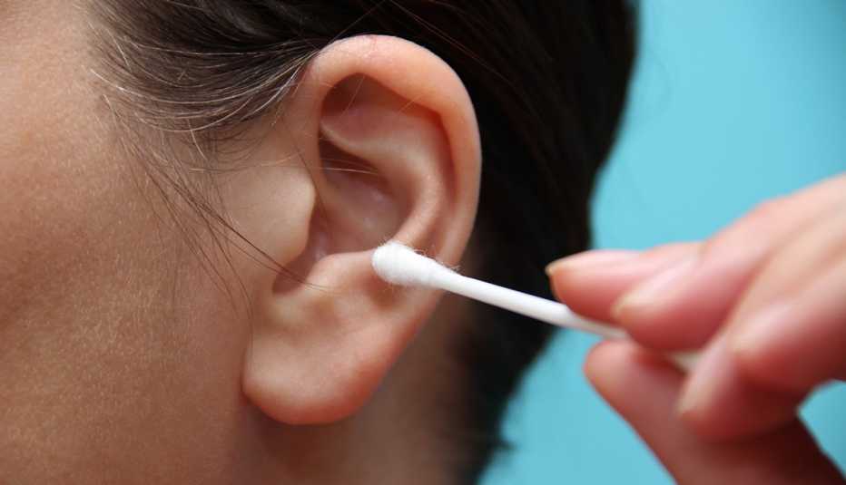 Una persona limpia sus oídos con un hisopo de algodón