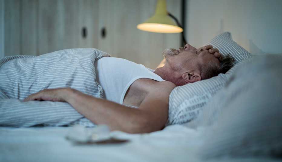 Un hombre acostado en su cama sin poder dormir