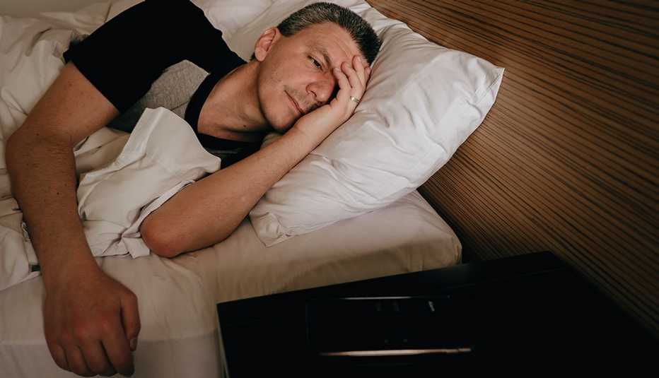Un hombre acostado en su cama sin poder dormir