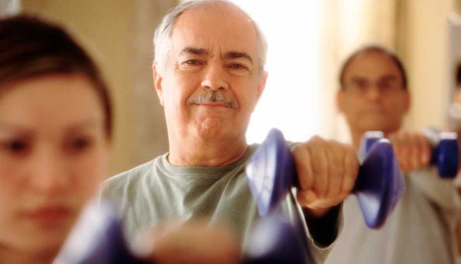 Hombre mayor levantando una mancuerna o pesa en una clase de aeróbicos.