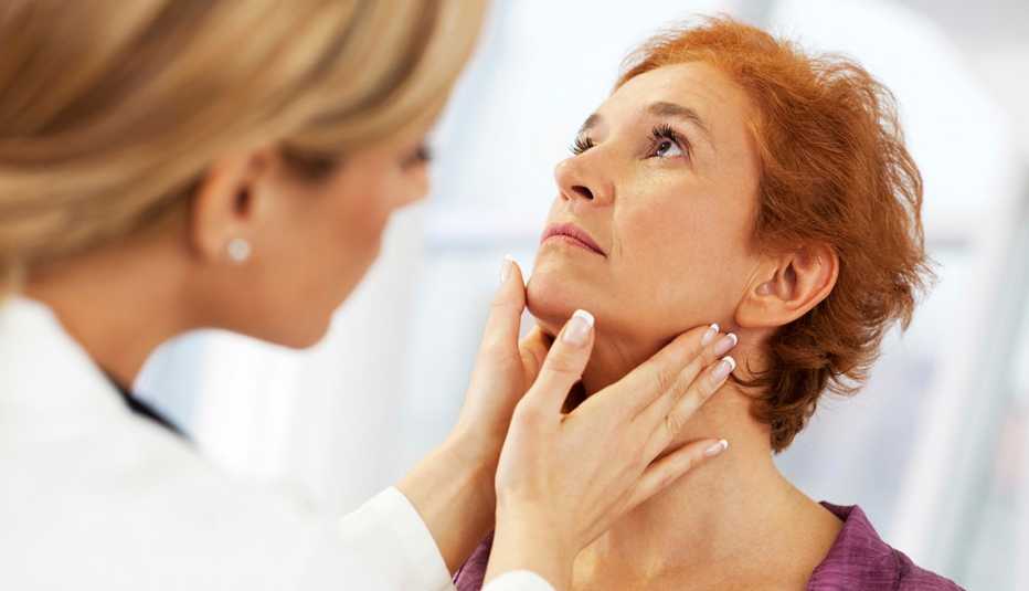 Doctora revisandole la tiroides a una paciente