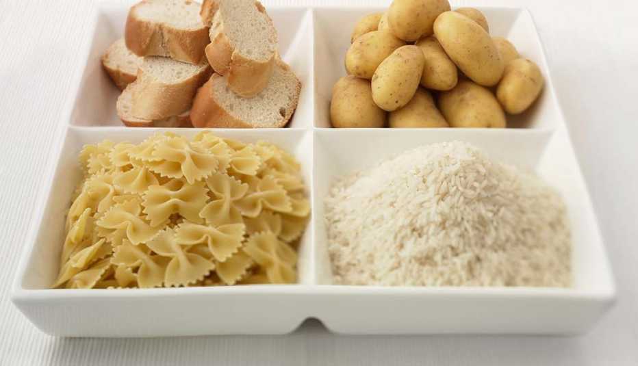 Plato de comida con 4 divisiones con pan, arroz, pan y pastas - Síntomas de la falta de carbohidratos en la dieta 