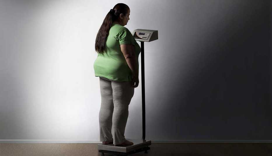 Mujer con sobrepeso en una pesa - Síntomas de la falta de carbohidratos en la dieta
