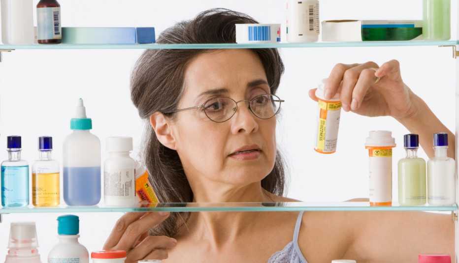 Mujer madura buscando medicamentos en un botiquín