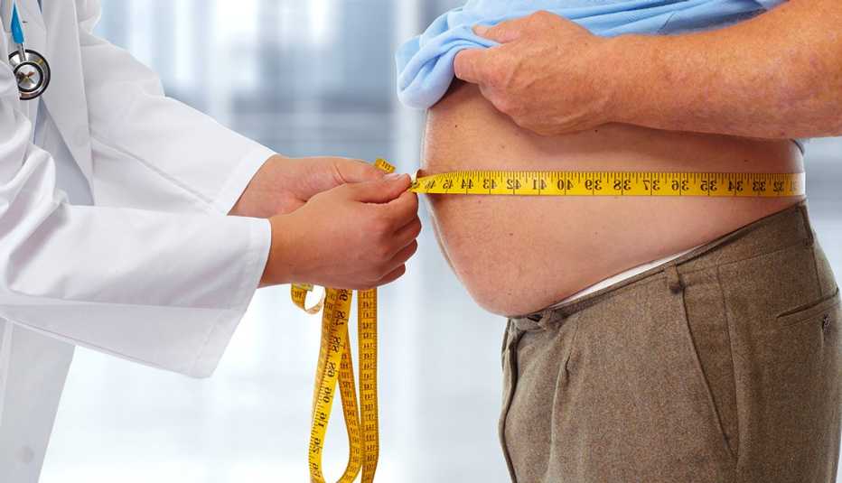 Médico midiendo la cintura de un paciente obeso