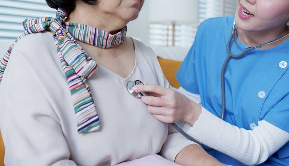 Una enfermera usa un estetoscopio para examinar el corazón de una paciente
