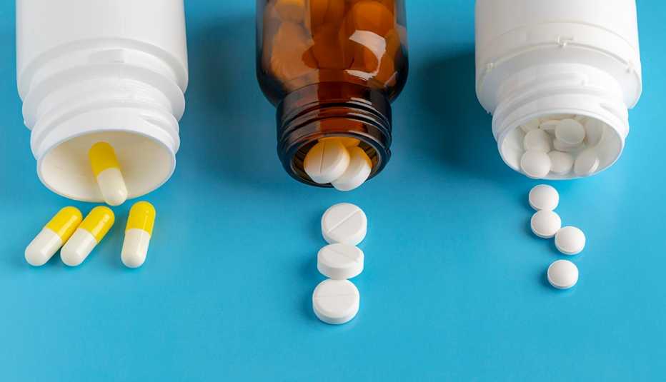 Tres frascos de medicamentos y diferentes pastillas