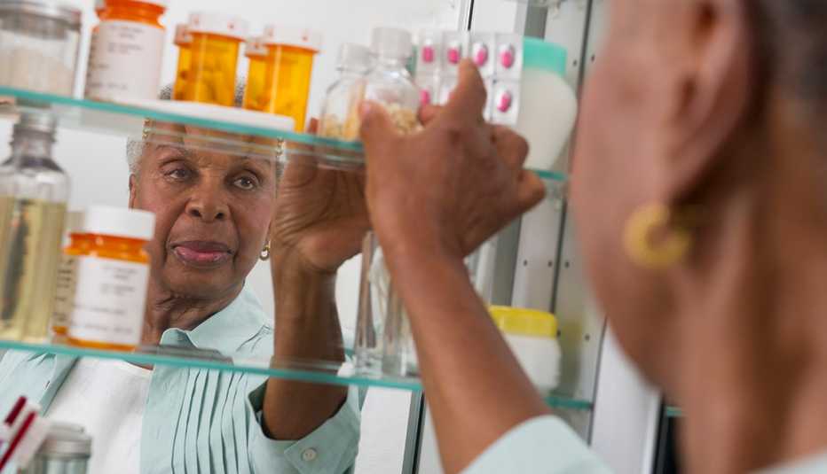 Una mujer busca un medicamento en su botiquín