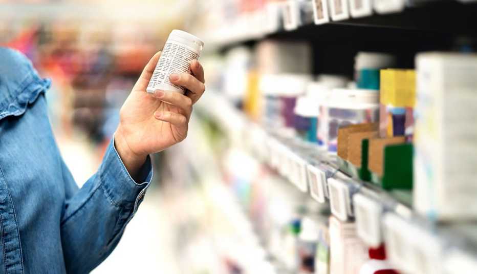 Cliente en una farmacia examina un frasco de pastillas que se vende sin receta