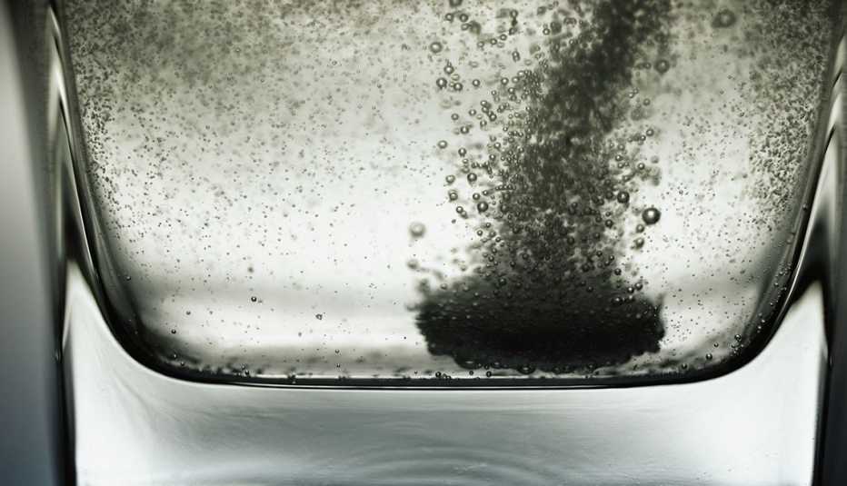 Una tableta efervescente se disuelve en un vaso con agua