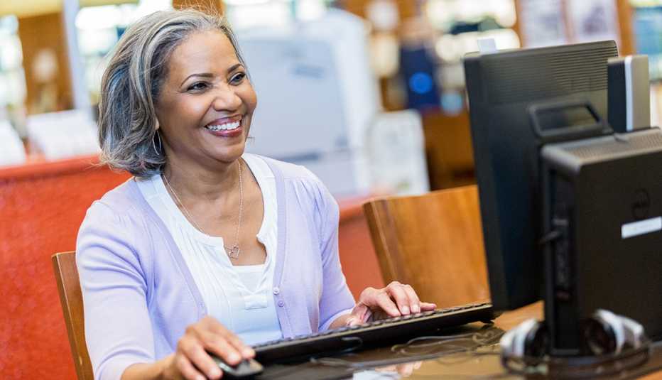 Una mujer utilza una computadora en una biblioteca