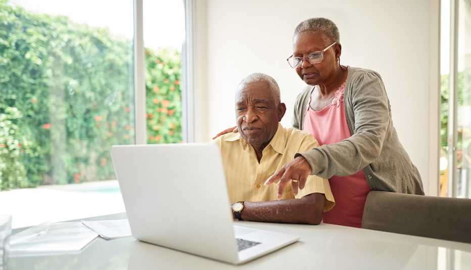 Un hombre hace una búsqueda en su computadora mientras su esposa observa