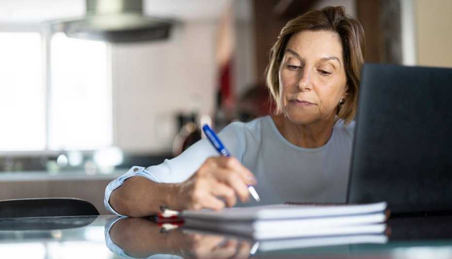 Una mujer lee en una computadora y toma notas