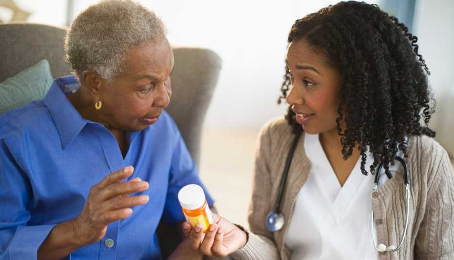 Mujer recibiendo un frasco de pastillas de una doctora