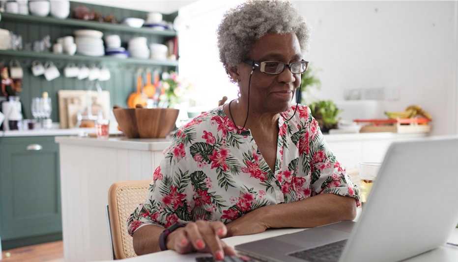 Una mujer frente a su computadora en la cocina de su casa