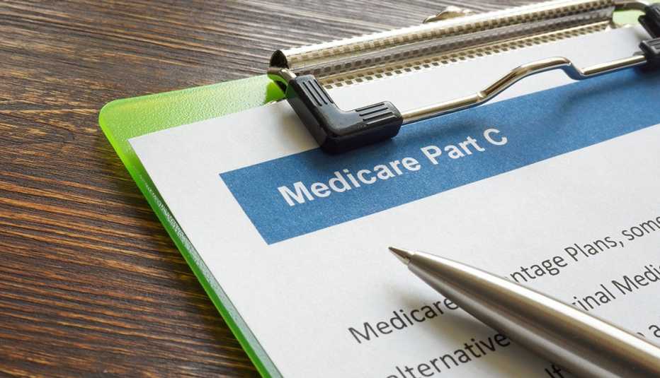 Un papel con información sobre Medicare parte C en un portapapeles y un bolígrafo sobre un escritorio