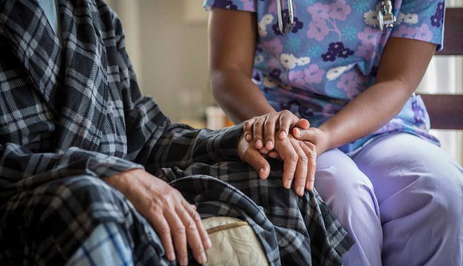 Una enfermera sostiene la mano de un paciente mayor
