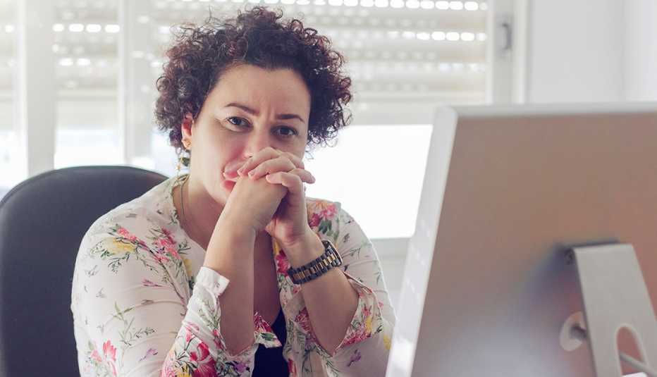 Una mujer, sentada frente a su computadora, intenta concentrarse