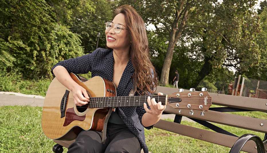 Xiyu Zhang, una musicoterapeuta, toca la guitarra en un banco en el parque